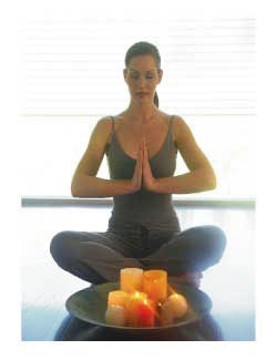 woman sitting in lotus pose with a tray of candles before her